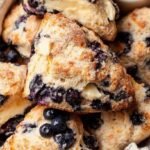 Freshly baked blueberry scones with a golden sugar crust on a wire cooling rack