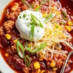 A bowl of thick turkey chili topped with fresh cilantro and lime wedges