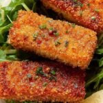 Golden brown crispy tofu schnitzel on a plate with lemon wedges and fresh parsley