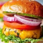 Four golden-brown chicken burger patties served on toasted buns with fresh lettuce and tomato