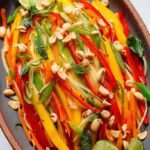 A vibrant bowl of shredded green mango salad with shallots, herbs, and peanuts