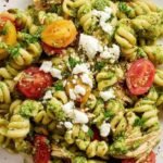 A bowl of tuna pesto pasta with cherry tomatoes and fresh basil