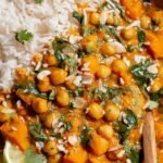 A steaming bowl of yellow butternut squash and chickpea curry topped with fresh cilantro
