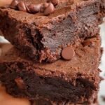 A stack of thick, dark chocolate fudgy healthy brownies on parchment paper.