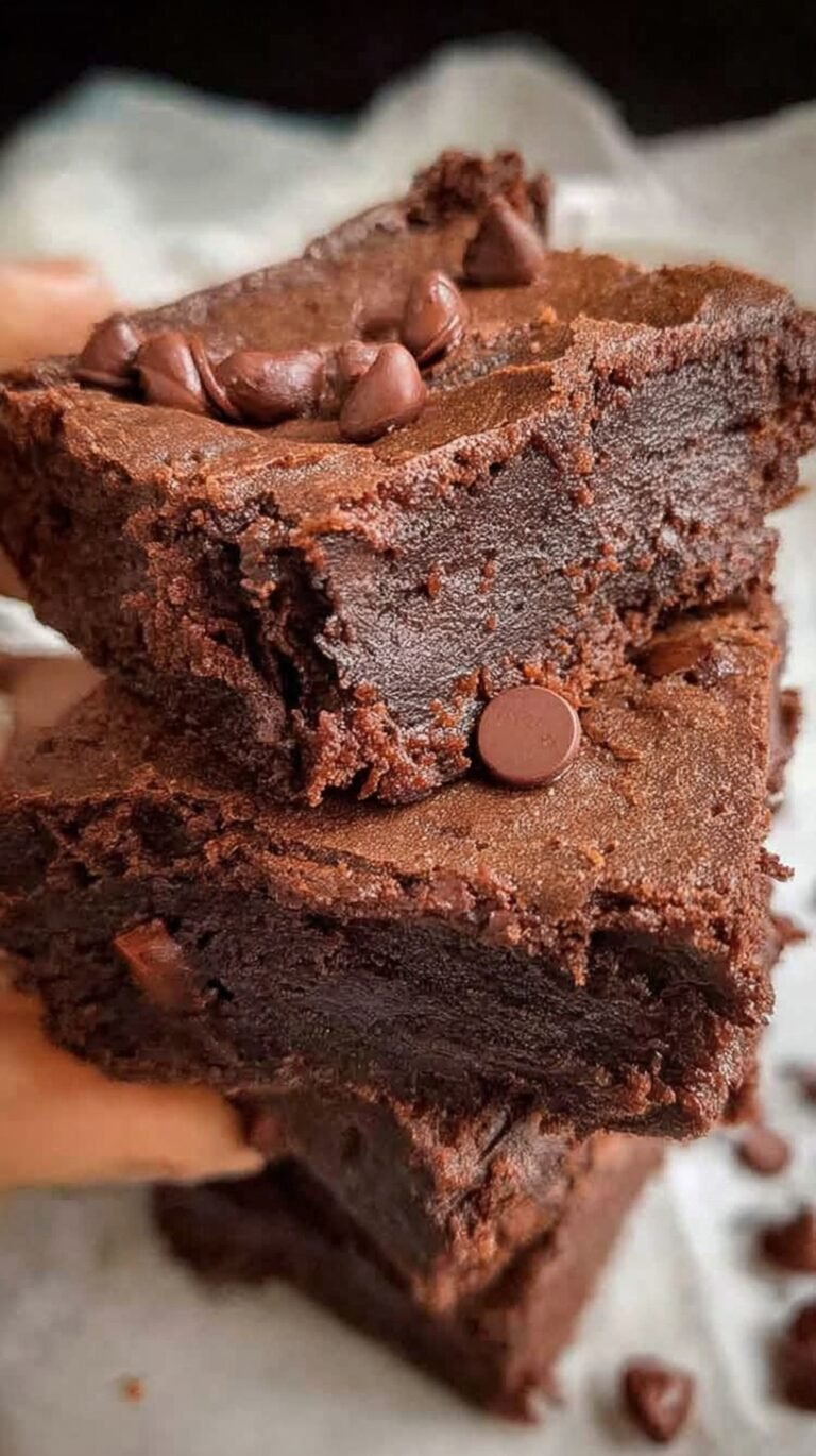 A stack of thick, dark chocolate fudgy healthy brownies on parchment paper.