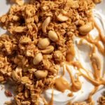 Golden brown clusters of peanut butter granola on a baking sheet