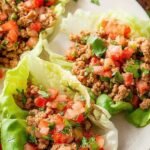 Savory ground beef filling inside crisp green butter lettuce leaves topped with cheese and avocado