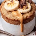 A single-serve mug filled with fluffy baked oats and melted chocolate chips on top.