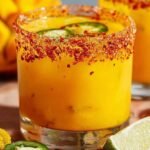 A vibrant yellow Spicy Mango Margarita in a salt-rimmed glass with a lime garnish.