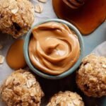 Close up of smooth peanut butter oatmeal balls stacked on a white plate