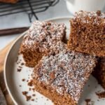 A slice of healthy gingerbread coffee cake with a walnut oat streusel on a white plate.