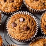 A stack of golden brown almond flour banana muffins on a wire cooling rack