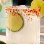 A tall highball glass of spicy ranch water with a Tajín rim and jalapeño slices