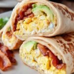 Large golden pancake rolled like a burrito filled with scrambled eggs, crispy bacon, and melted cheddar cheese.