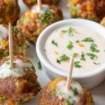 Golden brown turkey meatballs with visible green broccoli and melted cheddar cheese on a parchment-lined baking sheet.