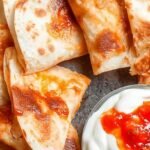 Two golden brown crispy air fryer quesadillas sliced into wedges on a plate with salsa