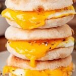 A toasted gluten-free breakfast sandwich with a fried egg, melted cheddar cheese, and crispy bacon.