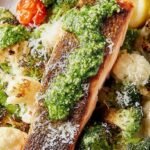 Pan-seared salmon with green pesto on top served with roasted asparagus and tomatoes