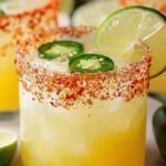 A fresh skinny spicy margarita in a salt-rimmed glass with lime and jalapeño garnish