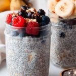 A glass jar filled with creamy oat milk chia pudding topped with fresh berries and a sprinkle of cinnamon.