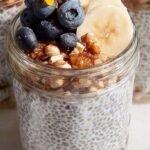 Two glass jars filled with creamy banana chia pudding topped with fresh banana slices and a sprinkle of cinnamon.