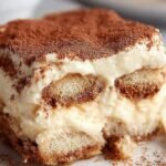 A glass dish of layered healthy gluten-free tiramisu topped with cocoa powder and dark chocolate shavings