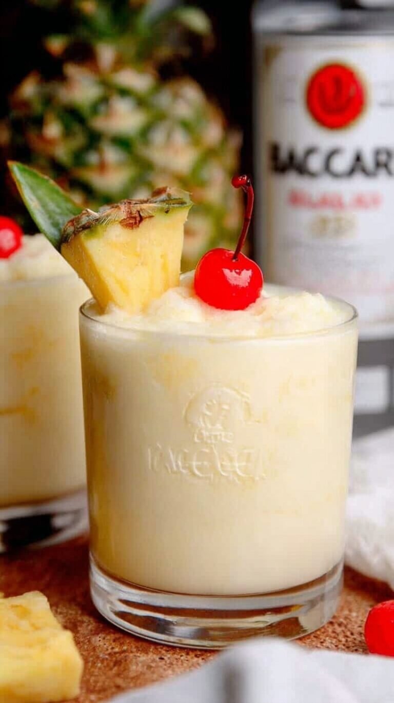 A chilled glass of Skinny Bacardi Pina Colada garnished with a fresh pineapple wedge on a sunny table.