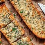Golden brown gluten-free garlic bread sliced on a baking sheet with fresh parsley