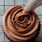 A bowl of smooth, velvety dairy-free chocolate frosting with a spreader.