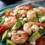 A bright bowl of shrimp avocado salad with cucumbers and red onions