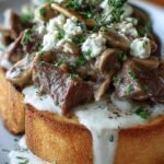 Slices of toasted French bread topped with creamy beef stroganoff and melted mozzarella cheese