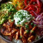 A colorful chicken fajita burrito bowl with grilled chicken, peppers, rice, and avocado