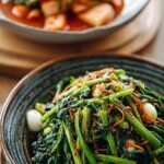 Two bowls of Korean spinach salad, one savory with sesame seeds and one spicy with red gochujang sauce