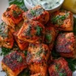 Golden brown air fried salmon cubes seasoned with spices in an air fryer basket