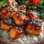 A colorful rice bowl topped with crispy glazed salmon bites, avocado, and cucumber