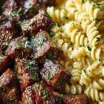 Golden seared steak cubes over creamy fettuccine pasta with fresh parsley garnish