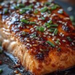 A glossy, dark honey garlic soy salmon glaze being brushed onto a fresh salmon fillet