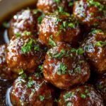 Slow cooker filled with beef meatballs, sliced mushrooms, and onions in a thick brown gravy.