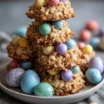 Chocolate peanut butter bird's nest cookies topped with colorful candy eggs on a baking sheet.