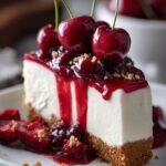 A creamy slice of no-bake cherry cheesecake with a graham cracker crust and bright red cherry topping.