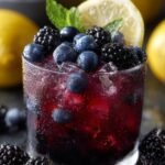 A glass bowl filled with glossy purple blueberry and blackberry compote with lemon zest