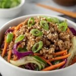 A steaming bowl of healthy egg roll in a bowl topped with green onions and sesame seeds