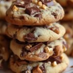 A stack of dark chocolate and peanut butter no-bake cookies on white parchment paper.