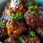 Slow cooker filled with beef meatballs, caramelized onions, and melted Gruyère cheese garnished with parsley.