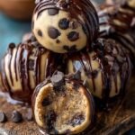 A platter of chocolate-covered brownie bombs with a cookie dough center sliced open.