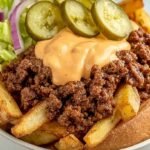 A colorful burger bowl with crispy potato fries, seasoned ground beef, fresh lettuce, and creamy sauce