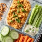 Four buffalo chicken wraps sliced and packed in meal prep containers with celery sticks.