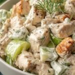 A bowl of creamy high protein chicken salad with fresh parsley and celery