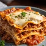 A bubbly, golden brown high protein lazy lasagna in a white baking dish topped with melted mozzarella and fresh herbs.