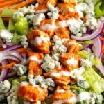 A fresh buffalo chicken chopped salad with blue cheese and ranch dressing in a white bowl